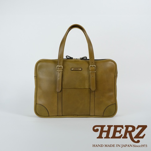 咖啡色皮革公事包，雙提把設計，正面有兩個可調節皮帶扣，中間有品牌標誌，整體簡潔大方。