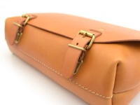 職人手作雙扣三用後背包，採用淺棕色皮革製成，配有黃銅色釦環和縫線細節。