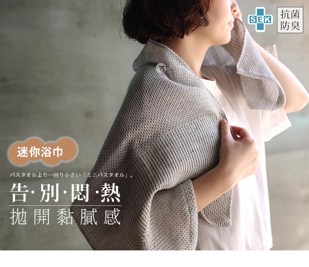 女性使用SEK抗菌防臭檜木鬆餅紋迷你浴巾，浴巾為灰色格紋材質，可掛於肩上或擦拭身體