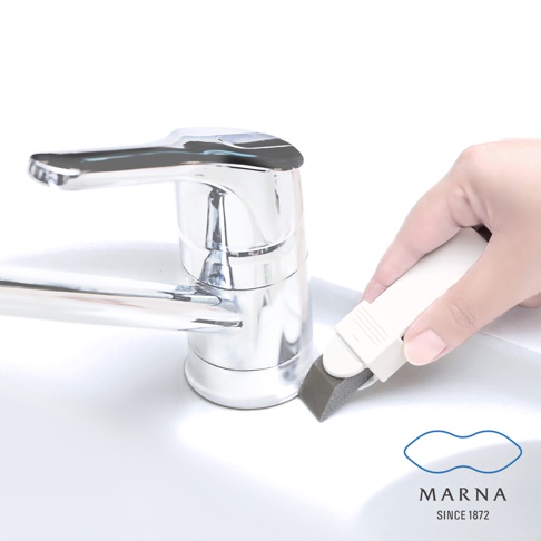 手持白色柄的灰色萬用去污橡皮擦，正在清潔水龍頭與白色水槽的接縫處。