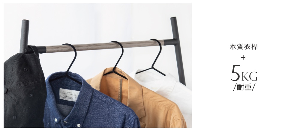 角落造型吊掛衣桿，木質掛桿搭配黑色金屬支架，掛有黑色帽子、藍色牛仔襯衫及淺棕色外套。