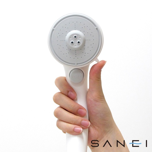 白色SPA沙龍蓮蓬頭，圓形噴頭上有密集的出水孔，中央有三個較大的出水孔，手柄處有一個灰色的「PUSH」按鈕，由一隻手握持。