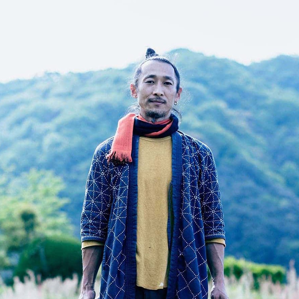 今治匹馬棉雙色圍巾，採用藍色與白色線條的幾何圖案，搭配橘紅色圍巾，展現獨特風格。