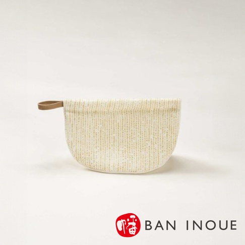 Tricot 棉麻防燙鍋套，米白色布料上織有淺黃色細緻條紋，一側有棕色皮革提環。