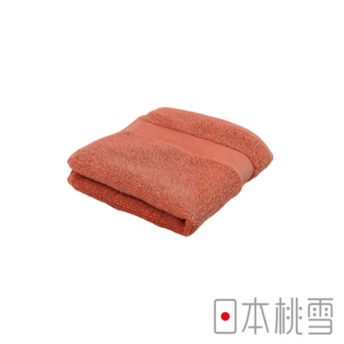 一條珊瑚色今治匹馬棉方巾，質地柔軟，對折後呈現立體感，邊緣有壓紋設計。