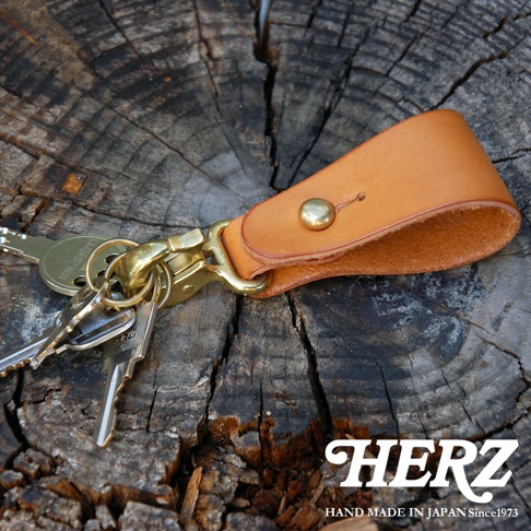 日本HERZ品牌手工製作的棕色皮革鑰匙圈，附有金屬扣環和鑰匙，置於木紋背景上