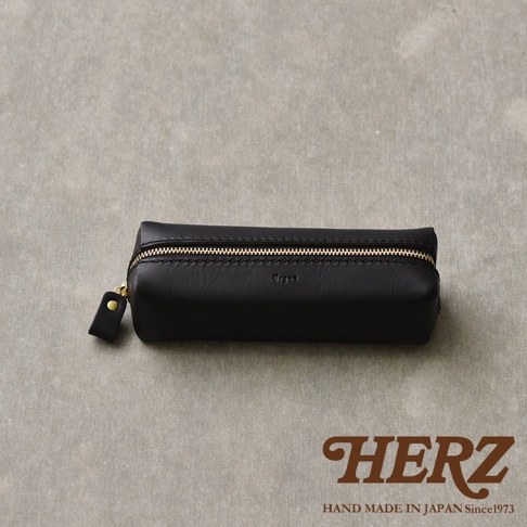 職人手作黑色皮革箱型收納筆袋，配有金色拉鍊和皮革拉環，袋身壓印有「Organ」字樣，整體簡潔俐落。