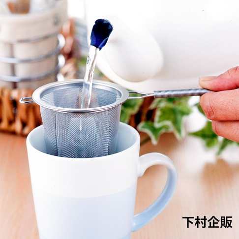 不鏽鋼深型濾茶網，網孔細緻，帶有可伸縮的手柄，正置於白色馬克杯中，上方有一壺正在注入熱水。