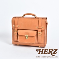 職人手作皮革學院風三用迷你後背包，採用天然皮革材質，呈現溫潤的淺棕色。包款設計有翻蓋式前袋、金屬鎖扣、可調式皮帶和扣環，另有頂部提把，整體風格簡約復古。