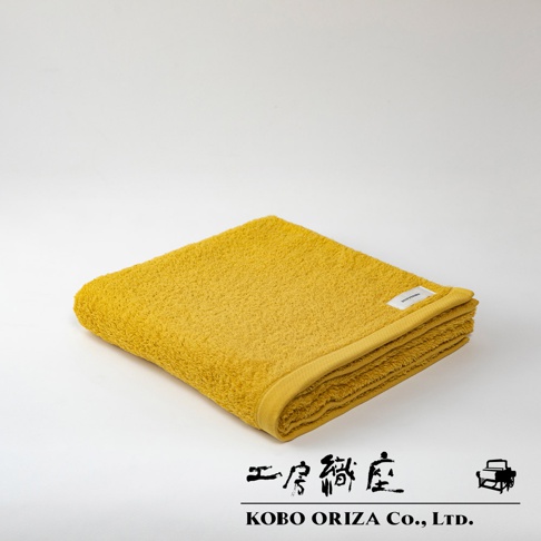 一條黃色SALA今治高密度耐洗超細纖浴巾，材質為細緻柔軟的棉，邊緣有品牌標籤。