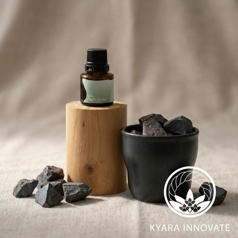 KYARA INNOVATE 擴香石，以木質底座承載的品牌精油瓶，旁為裝有炭黑色擴香石的黑色陶杯，周圍散落幾塊炭黑色擴香石，右下角為品牌標誌與日文字樣。