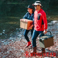 兩個人在河邊的碎石地上行走，一人手持淺棕色塑膠收納箱，另一人手持橄欖綠塑膠收納箱。