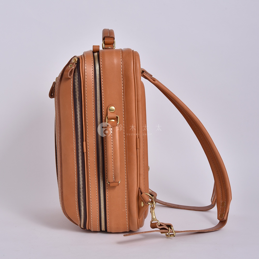 職人手作皮革兩用商務後背包 R-33，展示的是棕色款。包身由光滑皮革製成，側面有兩條拉鍊，上方有一個提把，肩帶為可拆卸設計，並配有金屬扣環。