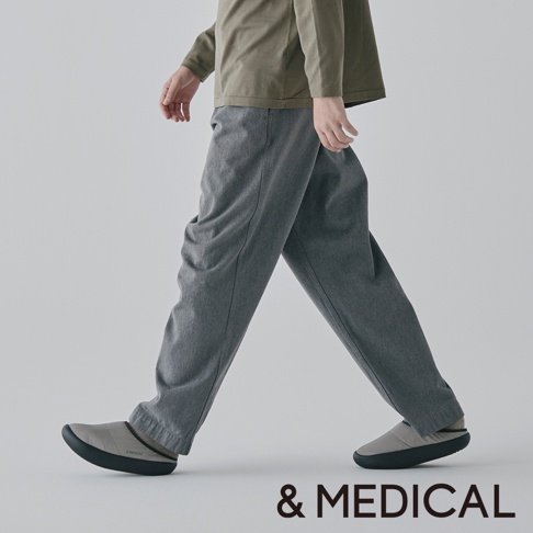 &MEDICAL 品牌標誌與模特穿著灰色長褲和灰色拖鞋的全身照