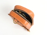 職人手作皮革兩用直立型斜背包，呈現天然棕色，以堅韌皮革製成，設有黃銅拉鍊和 D 型環。包包開口處可見內部藍色內襯及部分物品。