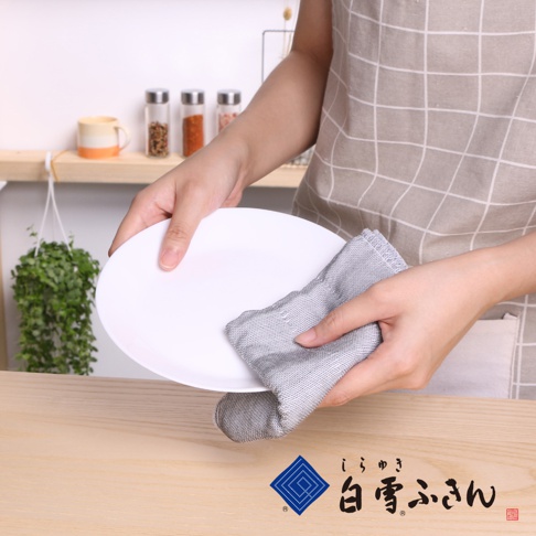 一雙手拿著白色盤子，用一塊灰色條紋的擦拭布擦拭。