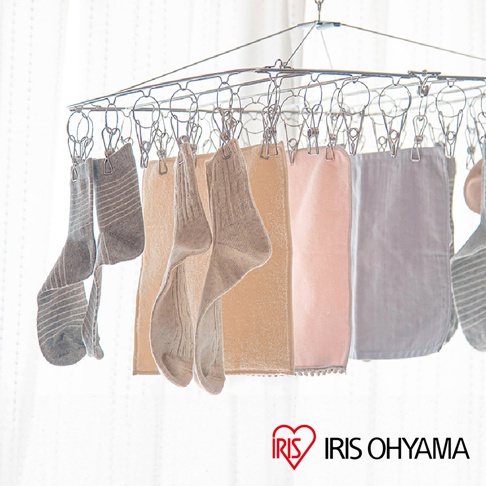 不鏽鋼曬衣架上掛著多雙灰白色條紋及素色襪子，以及淺黃、粉紅色、淺灰色的毛巾。