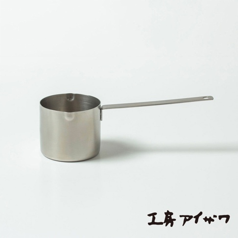 銀色不鏽鋼材質，圓柱形杯身，帶有長柄，杯緣有傾倒口。