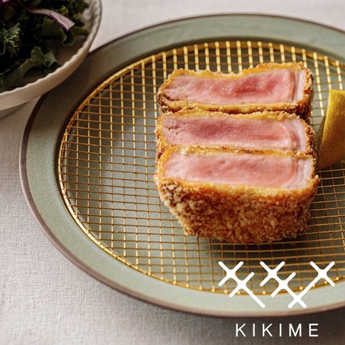 美濃燒綠色瀝油餐盤上，放著一個金屬網架，網架上擺放著三塊炸豬排，豬排外層裹著酥脆的麵包糠，內部肉質呈粉紅色。盤子邊緣有微妙的紋理。