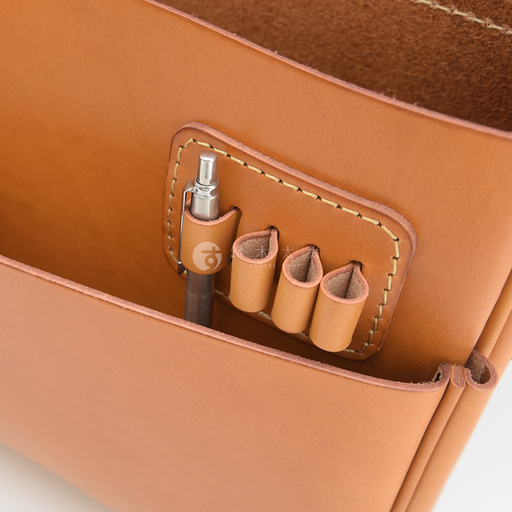 職人手作皮革公事包，採用天然棕色皮革，設有一個筆插和三個筆筒，細節處以黃色縫線裝飾，呈現簡約質感。