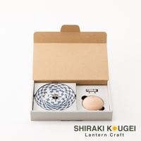 紙盒內裝有捲成圓形的藍白格紋繩索、一個木製圓形組件和一個金屬固定夾。