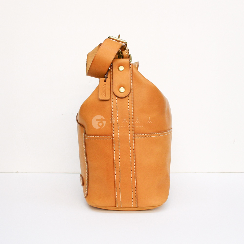 原色皮革厚實單肩波士頓包，採用縫線拼接設計，搭配可調節皮革背帶與金屬釦具。