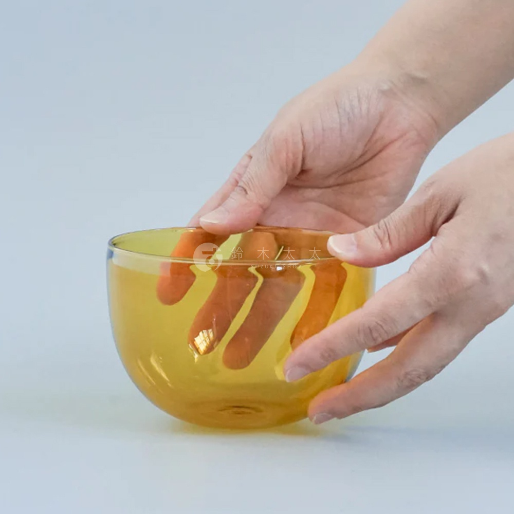 一隻手捧著一個琥珀色透明玻璃點心碗，碗內有手指印。