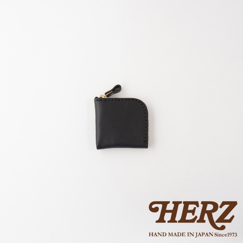 這是一款來自日本HERZ品牌的職人手作黑色Stare皮革零錢包，呈現方正圓角的簡約設計，頂部配有同色皮革拉環的金色拉鍊，整體外觀精緻小巧。