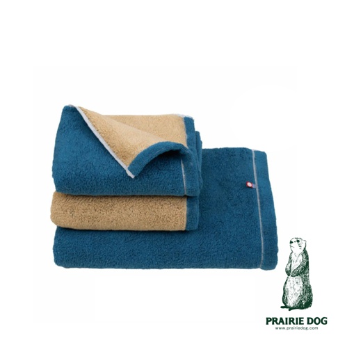 今治純棉翻轉色彩雙股紗半浴巾，藍色毛巾內襯為卡其色，疊放展示，毛巾材質柔軟，附有品牌標誌。