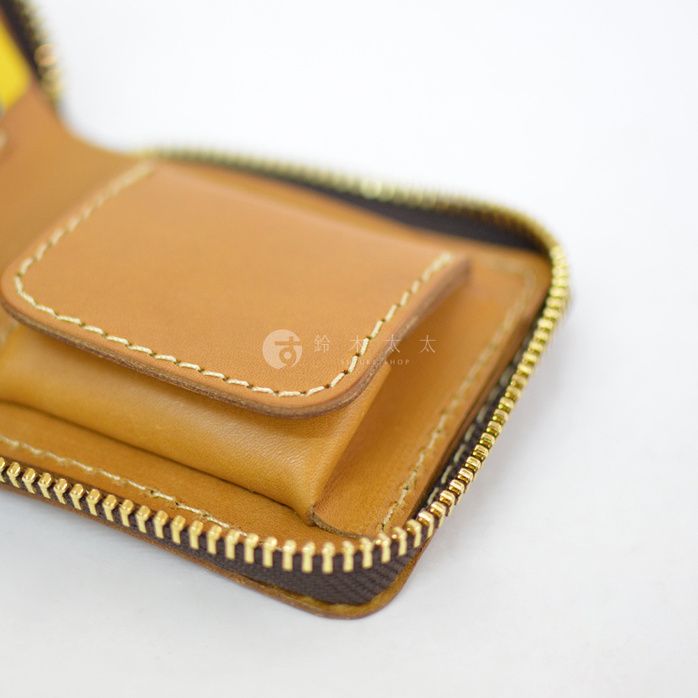 一張日本HERZ職人手作皮革短夾的特寫照片，呈現焦糖色Latigo軟皮革質感，夾層縫線整齊精緻，側面配有金色拉鍊，整體設計簡約且手工細膩。