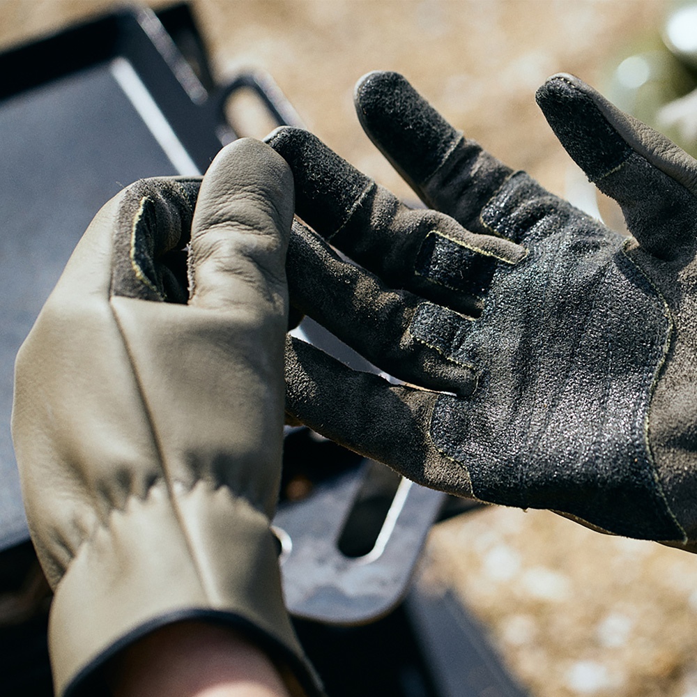 一雙 TA KI BE GLOVE 機能手套，左手為軍綠色皮革，右手為黑色絨面材質，手指處有防滑設計與魔鬼氈。