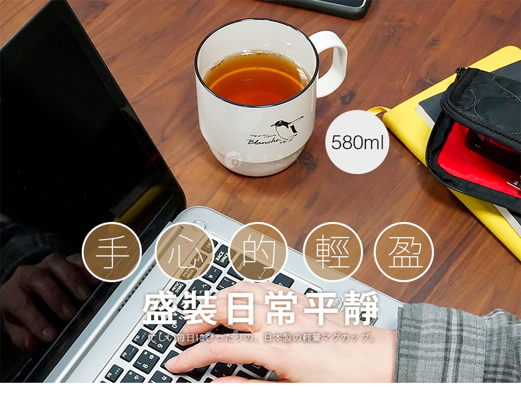 一張從上方俯瞰的桌面上，左方筆記型電腦正有手部在操作鍵盤，右上方放著一個裝有茶水的 Blanche 白色馬克杯，杯身上印有手繪企鵝圖案與 580ml 容量標示。畫面中間疊加了手心的輕盈盛裝日常平靜的白色標語，並配有一段日文描述，背景為木質桌紋與側邊的黃色筆記本及收納包。