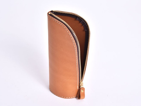 職人手作的直立式經典收納筆袋，採用淺棕色皮革製成，搭配金色拉鍊和縫線，設計簡潔實用。