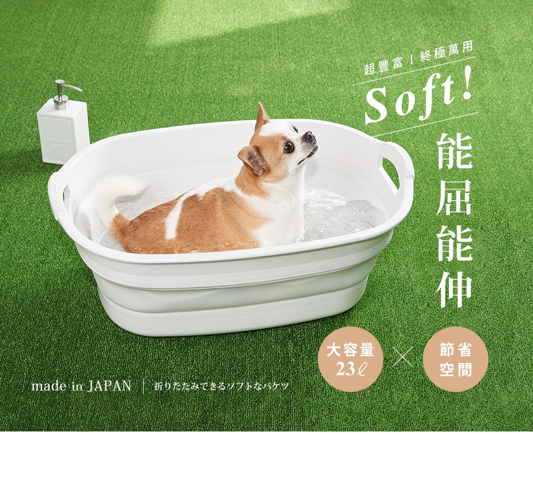 白色伸縮浴盆，盆內有一隻棕白相間的狗正在洗澡，周圍是綠色草地背景。浴盆為環保塑膠材質，設計有提把，可折疊收納。