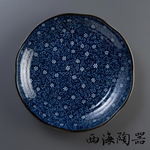 深藍色陶瓷圓盤，飾有白色小花與迴紋圖案，盤緣帶有金邊，整體呈現日式美濃燒風格。