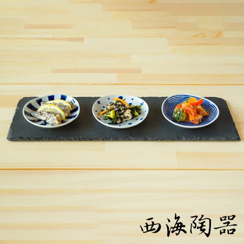 波佐見燒藍玉紋五件式醬料碟，三款小碟分別盛裝檸檬漬魚、蔬菜沙拉和章魚番茄，置於黑色石板上，背景為木紋桌面。