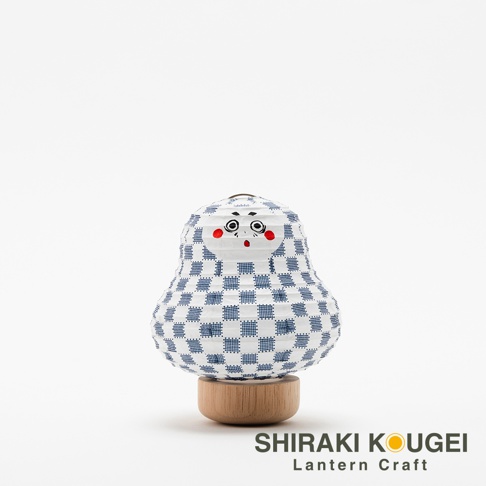紙質達摩不倒翁造型迷你提燈，白色燈身綴以藍色棋格紋，臉部繪有黑色眼睛、眉毛及紅色圓形腮紅，置於木質底座上。