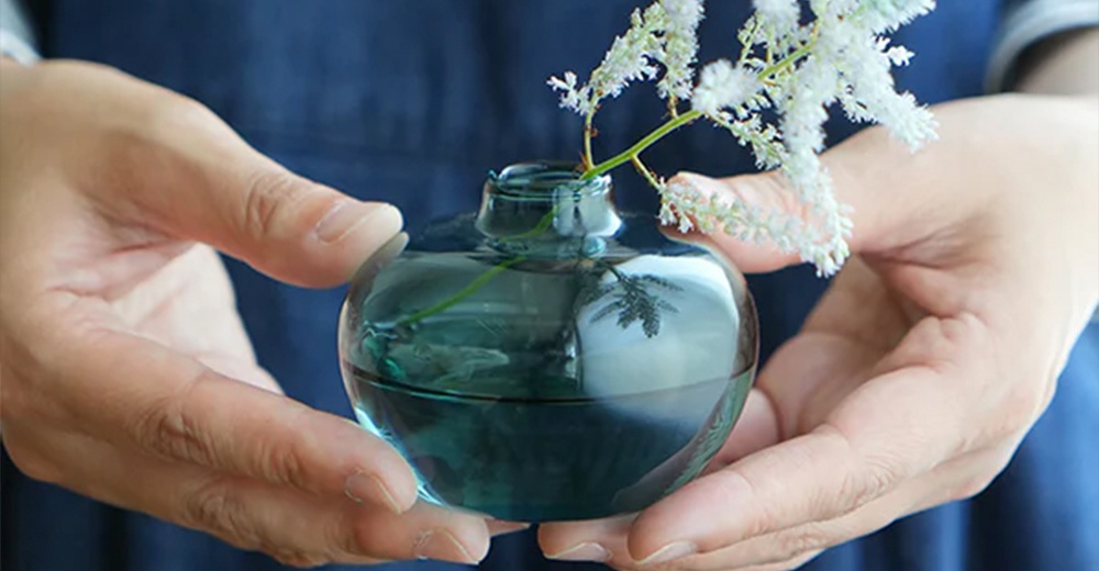 AXCIS Lua 多功能線香玻璃花器，淺藍色玻璃，內含白色線香，由雙手捧著，展現細膩質感