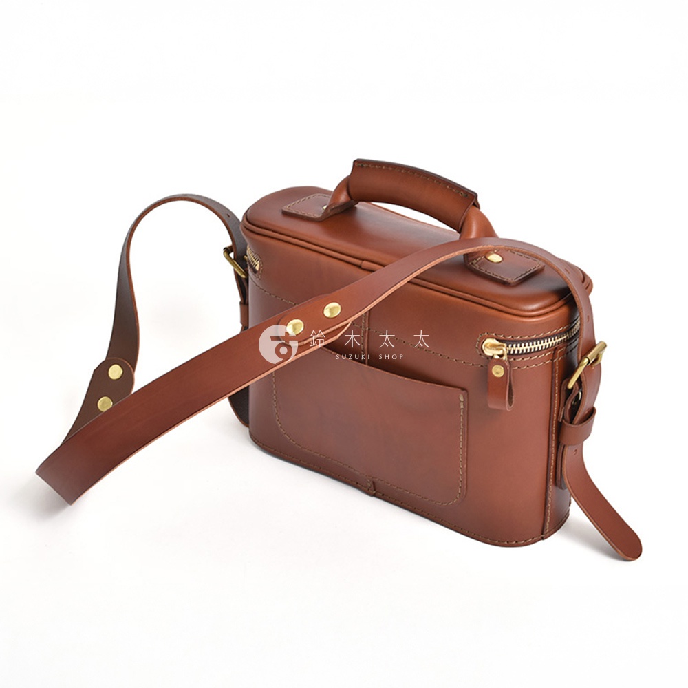 一個棕色的皮革相機包，配有可拆卸肩帶和頂部提把。