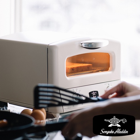 米白色復古多用途烤箱，設有透明觀景窗，內部有烘烤中的吐司，烤箱面板上有溫度和時間旋鈕，以及Sengoku Aladdin品牌標誌。