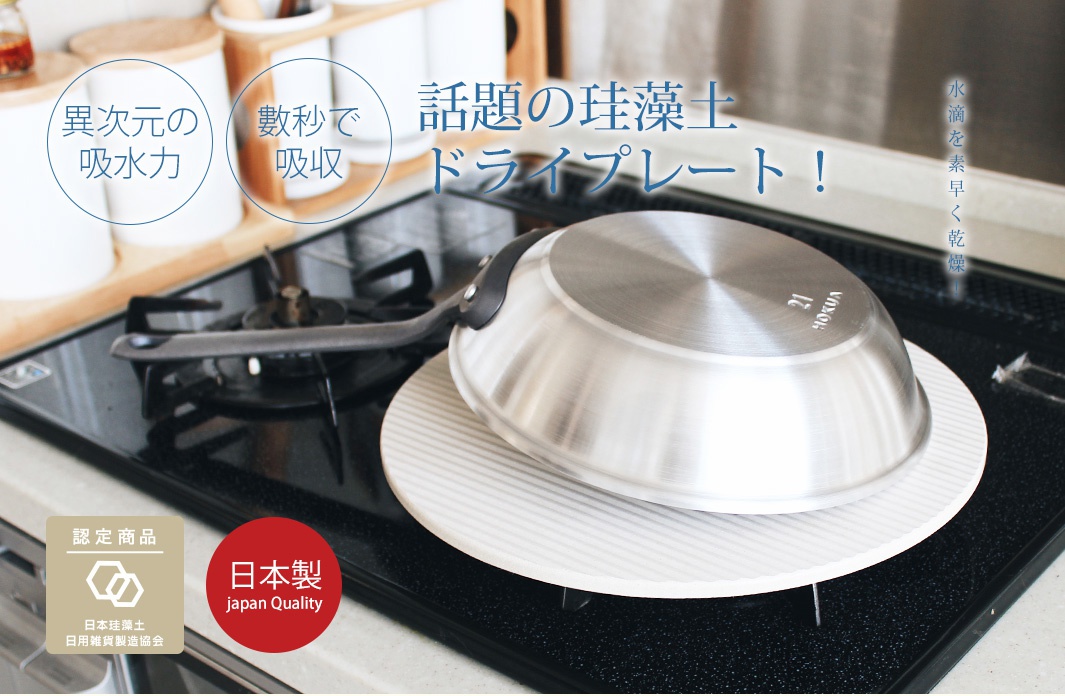 圓形珪藻土吸水置物墊，白色，表面有條紋。一個不鏽鋼鍋倒置在其上，置物墊放在黑色爐灶上。