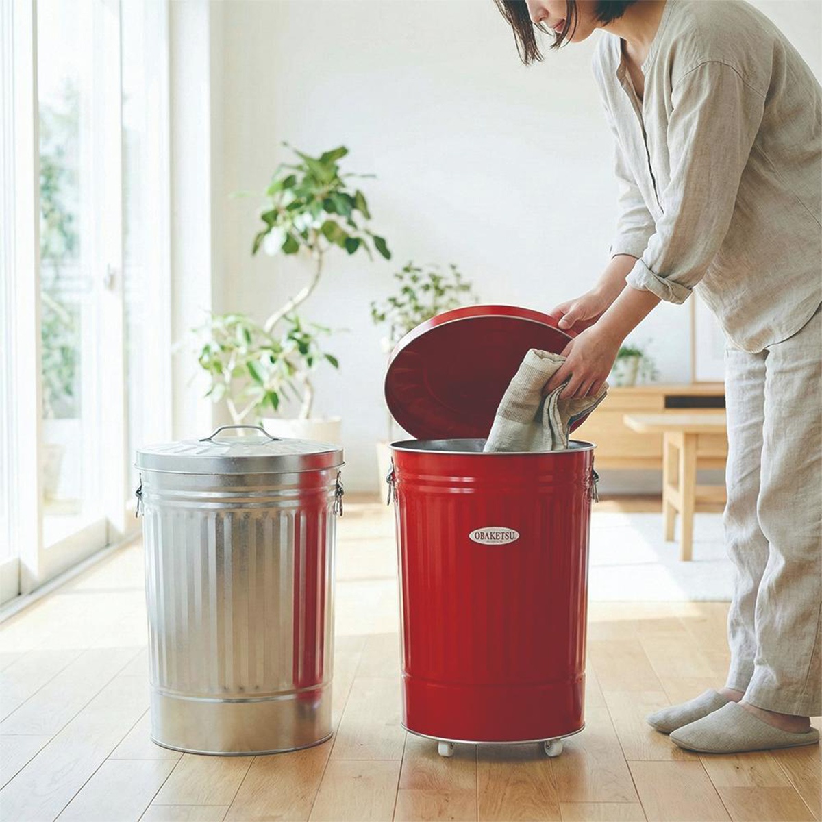 模式B： 一個紅色和一個銀色的金屬垃圾桶，一個女子正在將布料放入紅色垃圾桶。