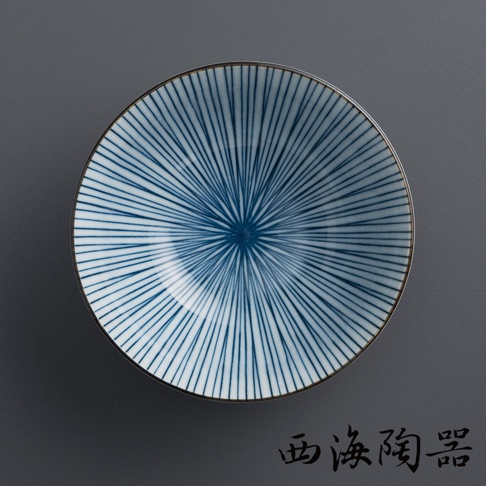 一個波佐見燒陶瓷粥碗，碗內繪有放射狀的深藍色細線紋路，碗緣為褐色。