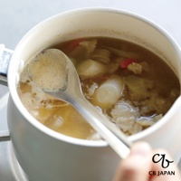 CB JAPAN 日本製不鏽鋼瀝汁匙正在從一鍋湯中撈取湯汁，湯中含有蔬菜塊和肉塊。