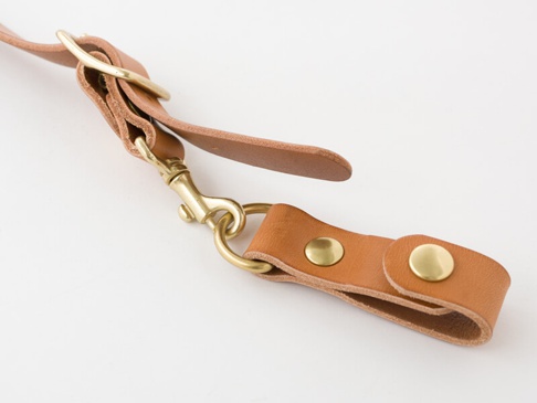 職人手作皮革背包用減壓胸前扣帶 (KO-2)，淺棕色真皮材質，搭配黃銅色金屬扣環、鉤扣及鉚釘，用於調節背包肩帶。