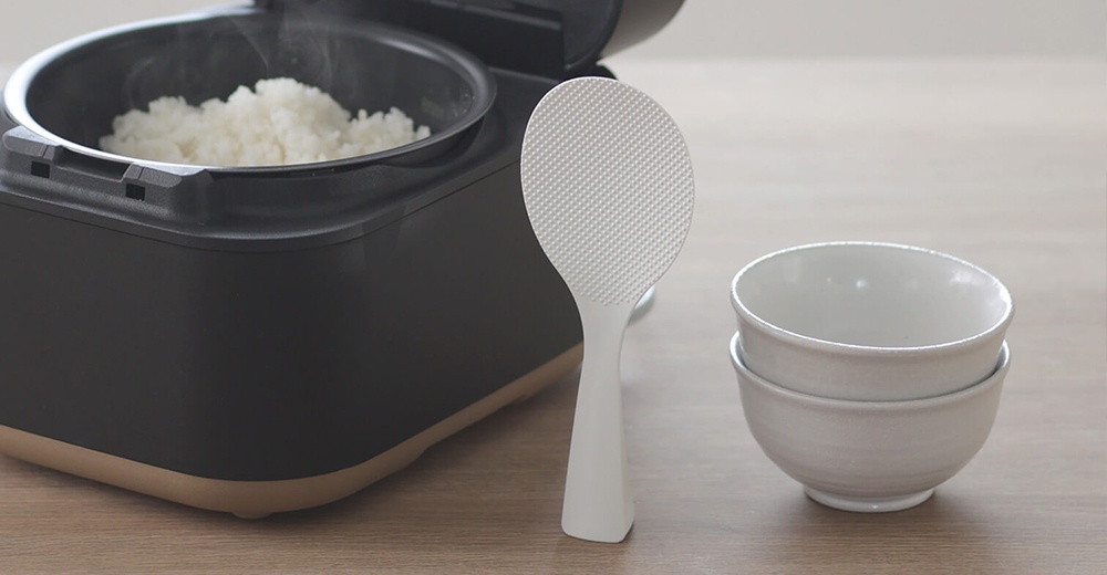 marna 站立式好握飯匙與炊飯鍋，以及疊放的白色碗盤