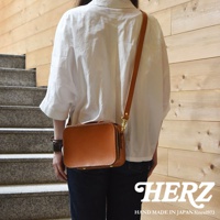 日本HERZ職人手作皮革兩用迷你小方包 CW-40 側背包，採用棕褐色硬質皮革製成，背面視角，展示包包的結構和金屬配件，下方有HERZ品牌標誌及「HAND MADE IN JAPAN Since1973」文字