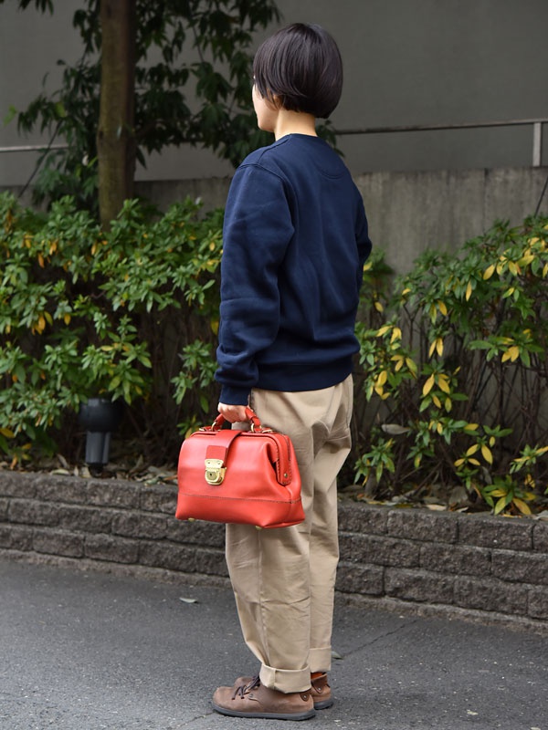 紅色皮革手提包，配有金色鎖扣和頂部提把，可作單肩包使用。