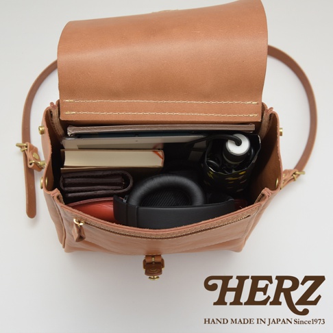 職人手作皮革屋瓦風後背包，淺棕色，內部裝有書本、錢包、耳機和雨傘，展現其收納空間。