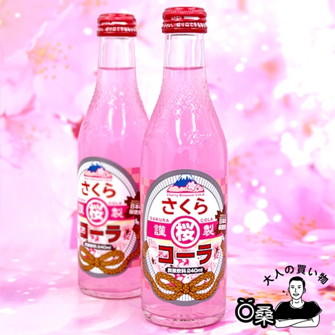 兩瓶粉紅色玻璃瓶裝的期間限定汽水，瓶身印有日文「さくらコーラ」和富士山圖案，搭配紅色瓶蓋。